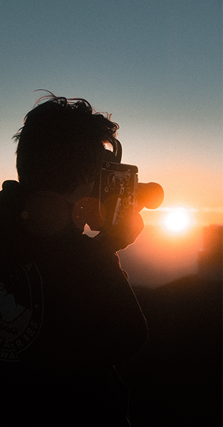 Documentary film-maker using handheld super 8 camera to film sunset in Africa